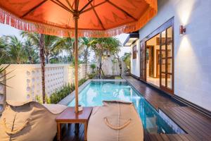 a swimming pool with two chairs and an umbrella at Dijero at Umah Bali in Ubud