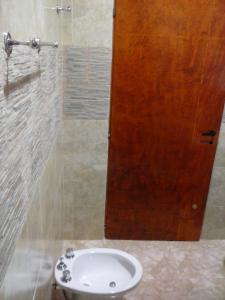 a bathroom with a sink and a wooden door at Departamentos por dia EL TREBOL in Paso de los Libres +11 photos