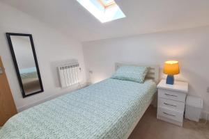 a bedroom with a bed with a lamp and a mirror at Stable Barn Apartment in Saint Breward