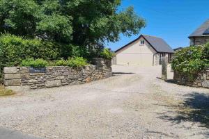 a stone wall and a building with a garage at Stable Barn Apartment in Saint Breward