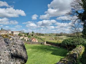 uma vista para um campo com uma parede de pedra em Hôtes de Saint Emilion II em Saint-Émilion