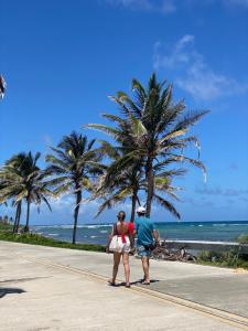 dwoje ludzi spacerujących po chodniku w pobliżu plaży w obiekcie San Andrés , apartamento resort w mieście El Cove