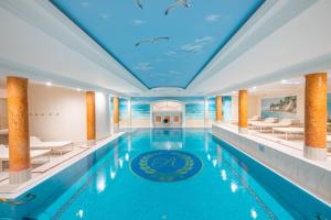 a large swimming pool with a blue ceiling with a dolphin painting at Rugard Thermal Strandhotel in Binz