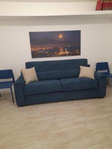 a blue couch in a living room with a painting at Pastel blue house x 5 people in Corso above metro Montesanto in Naples