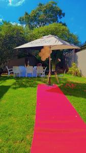 a red carpet with an umbrella on top of a table at DreamWest Living The Guesthouse in Krugersdorp
