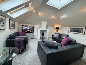 a living room with two couches and a tv at School Path Ironbridge Townhouse with Roof Terrace in Ironbridge