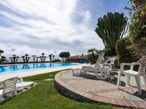 a group of white chairs sitting next to a swimming pool at Apartment Rosy by Interhome in Costarainera +37 photos