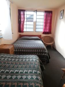 a hotel room with two beds and a window at Hospedaje Frankenstein in Cusco