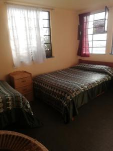 a bedroom with two beds and two windows at Hospedaje Frankenstein in Cusco