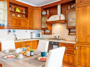 a kitchen with wooden cabinets and a table with chairs at Apartment Belvedere by Interhome in Bellano