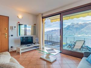 a living room with a television and a balcony with mountains at Apartment Belvedere by Interhome in Bellano