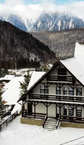 ein schneebedecktes Haus mit Bergen im Hintergrund in der Unterkunft 30 Forest, Azuga in Azuga