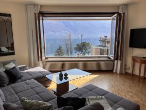 een woonkamer met een bank en een groot raam bij Apartment Suite Classic-16 by Interhome in Ascona