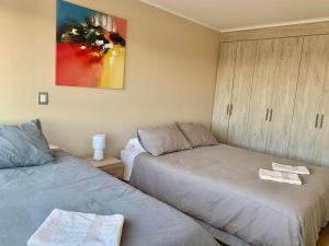 1 dormitorio con 2 camas y un cuadro en la pared en Departamento Centro Chillan - Parking -Vista - Factura, en Chillán
