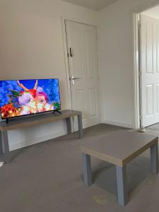 uma sala de estar com uma televisão de ecrã plano sobre uma mesa em Village House Cardiff - Close to A48 and M4 em Cardiff