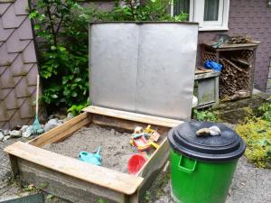 a sandbox with a green trash can in front of a refrigerator at Apartment Barmettlenstrasse 26 by Interhome in Engelberg