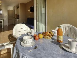 a table with a blue table cloth with a basket of fruit at Apartment Les Rivages de Coudoulière-8 by Interhome in Six-Fours-les-Plages