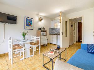 a living room with a blue couch and a kitchen at Studio Le Béniguet by Interhome in Légenès
