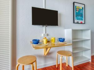 a table with two chairs and a tv on a wall at Apartment Primavéra-7 by Interhome in Lacanau-Océan