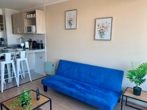 uma sala de estar com um sofá azul e uma cozinha em Departamento Centro Chillan - Parking -Vista - Factura em Chillán