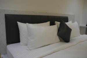 a bed with white pillows and a black headboard at Goldeye's Inn in Erode +1 photo