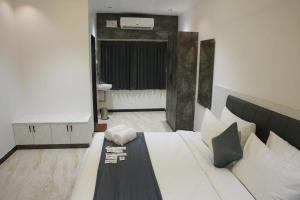 a bedroom with a large white bed and a bathroom at Goldeye's Inn in Erode