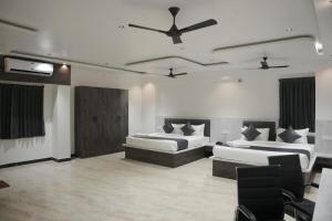 a bedroom with two beds and a ceiling fan at Goldeye's Inn in Erode