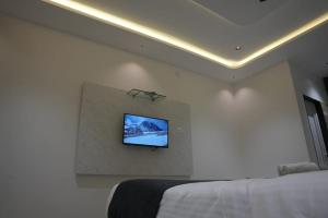 a bedroom with a tv on a white wall at Goldeye's Inn in Erode