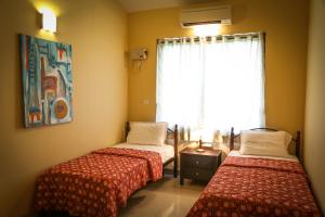 two beds in a room with a window at Majorda Beach Holiday Apartment in Majorda