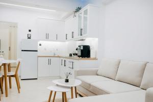 a white living room with a couch and a kitchen at White&Wood in Patra