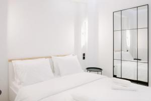 a white bedroom with a white bed and a mirror at White&Wood in Patra