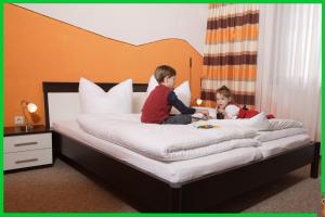 dwoje małych dzieci siedzących na łóżku w obiekcie Landhotel Waldesruh w mieście Furth im Wald