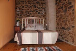 1 dormitorio con cama y pared de piedra en El Urogallo de Rucayo, en Boñar