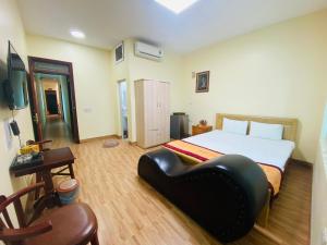 una camera con un grande letto e una sedia in pelle nera di HOTEL HOÀNG LONG a Dien Bien Phu