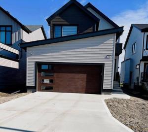 a house with a garage door in front of it at Private Basement Suite with comfort in Winnipeg