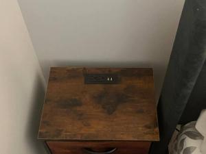 a wooden night stand with a remote control on it at Private Basement Suite with comfort in Winnipeg