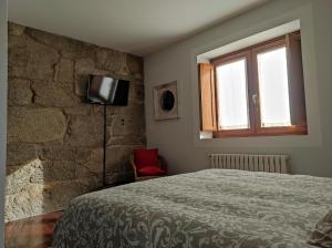 a bedroom with a bed and a stone wall at Casa Camino Santiago-Fisterra in Amés