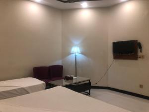 a room with two beds and a flat screen tv at Dove Inn Hotel Kalma Chowk in Lahore