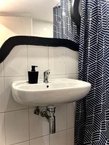 a white sink in a bathroom with a black and white shower curtain at ALTiDude in Cluj-Napoca