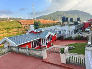 ein rotes Haus mit einem Dach auf dem Balkon in der Unterkunft QUEENS COTTAGE - individual cottage in Udagamandalam