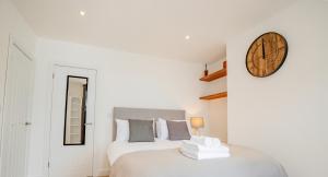 a bedroom with two beds and a clock on the wall at Modern flat with garden in city centre in Hereford