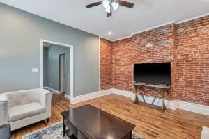 a living room with a brick wall and a flat screen tv at Central St Louis apartment 1W in Soulard