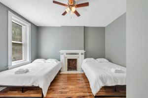 two beds in a room with a ceiling fan at Central St Louis apartment 1W in Soulard
