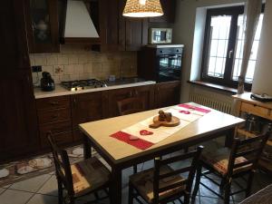 une cuisine avec une table en bois, des chaises, une table et une table dans l'établissement La casa del bosco, à Aoste