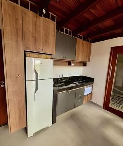 una cocina con electrodomésticos blancos y armarios de madera en Refúgio paradisíaco em búzios., en Búzios
