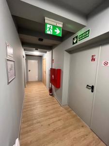 un pasillo de un pasillo del hospital con una puerta y señales de salida en 3 Budget Stay Apartments, en Zgorzelec