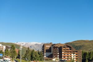 un bâtiment avec des montagnes en arrière-plan dans l'établissement Résidence Pierre & Vacances Les Bergers, à L'Alpe-d'Huez