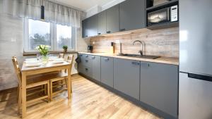 una cucina con tavolo, lavandino e frigorifero di Szafirowa, Sun & Snow a Mielno