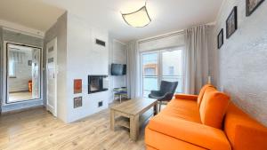 a living room with an orange couch and a table at Apartamenty Sun & Snow Szafirowa in Mielno