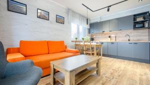 a living room with an orange couch and a table at Apartamenty Sun & Snow Szafirowa in Mielno